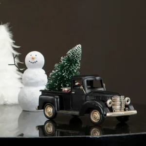 Svart lastbil i metall med en julgran på flaket